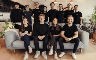 The Merge San Francisco team poses on a couch in the office for a group photo.