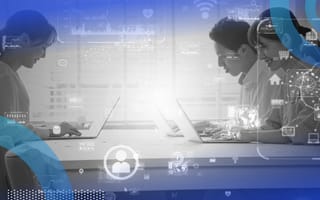 Three people work on laptops at a table with a technical overlay