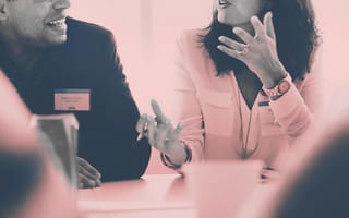 Employee engagement, two employees talking at a table during a meeting.