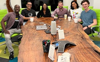 Fetch employees smile at the camera from around a conference table.