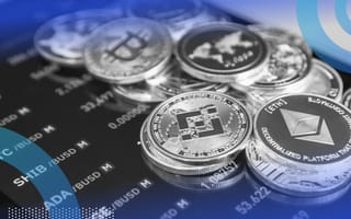 A stack of crypto coins on top of a smartphone with a market reading on it