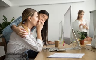 A teammate comforting another teammate who is looking at a computer screen.