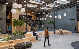 An employee walks through the open GoodRx office space filled with lanterns and plants.