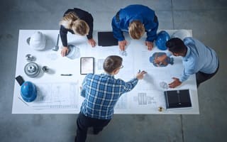 An overhead view of four team members gathered around a table as they collaborate.