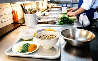 professional kitchen with ingredients prepped and cook chopping in the background
