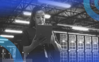 A woman looks at a tablet in front of a row of servers