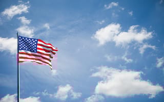 The American flag waves in front of a cloudy background