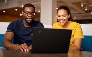 A man and a woman smile at a laptop computer