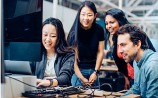 A group of Covariant employees sit at a computer together working on a project.