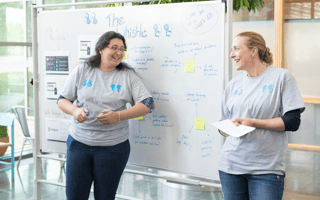 Two Redgate co-workers smile as they lead a presentation.