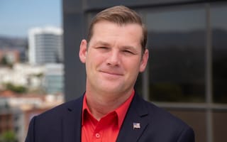 A man wears a red button up shirt and black blazer