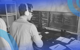 A man wears a headset and works on code at a desktop