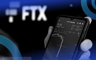 A person looks at a smartphone showing plunging stock prices in front of an FTX logo