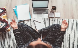 A woman meditates in front of her computer.