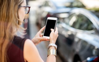 A woman checks her cell phone outside her car