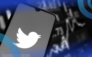 The Twitter logo on a smartphone in front of a stock ticker