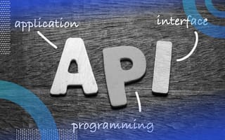 API image of the letters API on a wooden table. There are arrows to each corresponding word spelling out the acronym, application programming interface