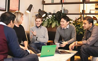 Chronosphere co-founded by CTO Rob Skillington and CEO Martin Mao gather around a table in the office with other employees.