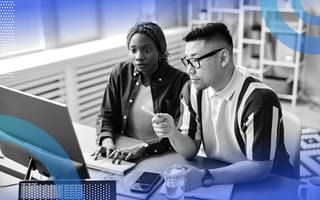 JavaScript image of two people sitting together in front of a computer. A Black woman with braids types and an Asian man is in the middle of speaking.