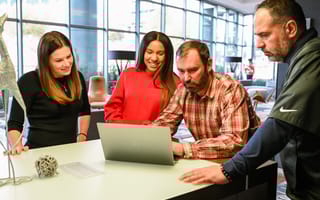 Members of the Reibus team gather around a laptop at a conference table