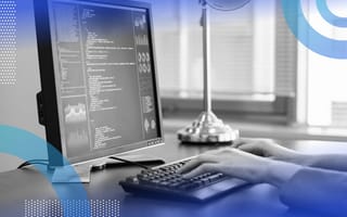 Python image of a programmers hands on a desktop keyboard and a monitor with code on it.