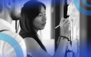 Recruiting operations image of a woman writing on a board. A man stands slightly behind her reading what she's writing.