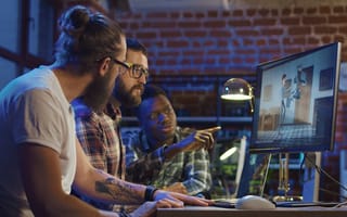 A group of men sitting at in front of a computer co-working on creating a new cartoon