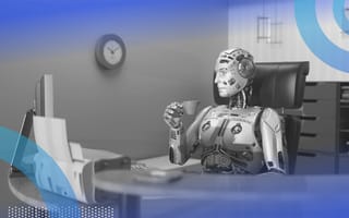 A robot drinks from a mug while sitting at a computer workstation