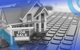 A house with a for-sale sign sits on a laptop keyboard