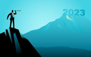 Businessman standing on a mountain, looking at the year 2023 through a telescope.
