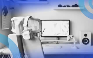 i/o input/output image of a computer on a desktop with a chair in front of it. A pair of headphones rests on the chair's headrest.