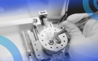 Nanotechnology image of a scientist preparing nanomaterials for a Scanning Electron Microscope (SEM) machine in a laboratory. We only see the slide, the scientist's gloved hand a tool they hold for manipulating the nanomaterial.