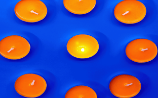 A single candle lit excluded from a group of unlit candles.