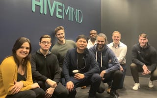 The Hivemind team poses in front of their logo on the wall of their new NYC headquarters.