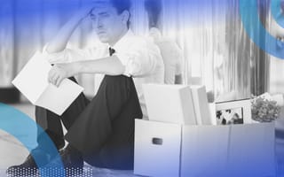 A man holds a letter and looks upset next to a box filled with office supplies