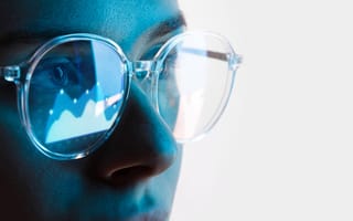 A person wearing glasses with data in the reflection.