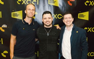 Excel's leadership team poses in front of a conference banner