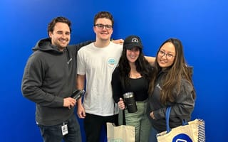 New BigTime employees pose in front of a cobalt blue wall with their Camp BigTime swag