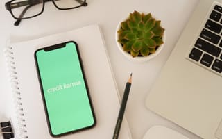 A phone shows Credit Karma's logo next to a laptop and succulent