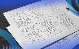 Wireframes image of a piece of paper with a desk with six wireframes drawn on it