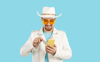 A man in Western wear types on his phone.