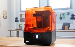 A Star Wars helment that was printed by Formlabs' 3D printer sits on a table next to the printer.