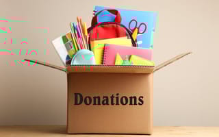 Notebooks, pens and other school supplies fill a donation box.