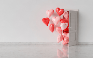 Red, pink and white heart balloons coming out of a white door into a white room