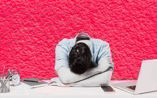 An employee lays their head down on their desk.