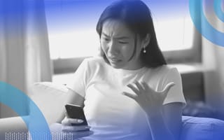 A woman looking angrily at a cell phone. Mercury in retrograde can spark communication snafus, so move carefully to avoid them.