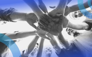 A group of people put their hands into the middle of a circle