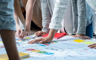 A product development team stands around a design plan.