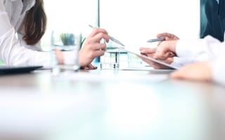 A consultant points to a tablet as they advise a client.
