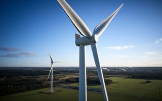 5 Top Wind Power Companies Two wind turbines stand tall in a field to capture energy from the wind.